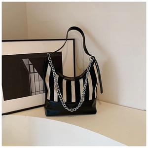 Close-up of black and white striped shoulder bag with a silver decorative metal chain