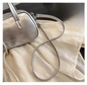 Detail of silver textured leather bag with pearl chain strap and zip closure