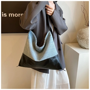 Detail of blue textured fabric and black leather splicing on large shoulder tote bag