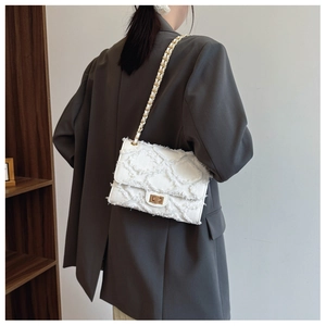 Détail du sac bandoulière en tweed blanc avec bords effilochés et chaîne dorée
