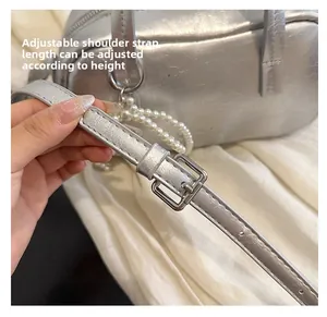 Detail of silver textured handbag featuring adjustable buckle strap and pearl chain