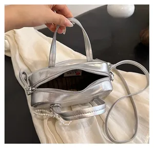 Detailed view of silver mini bag interior with black striped lining and pearl charm detail