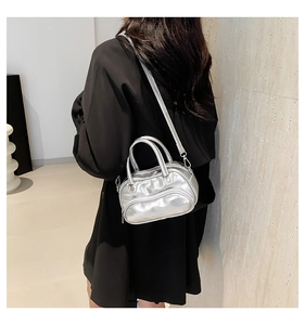 Detail of silver metallic boston bag showing the adjustable strap on a black blazer