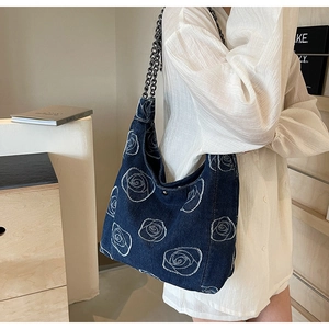 Detail of dark blue denim tote with white rose embroidery and black chain strap