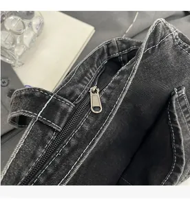 Nahaufnahme von silbernem Reißverschluss und Kontrastnähten auf schwarzer Denim-Tasche