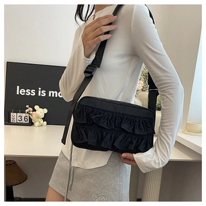 Detail der schwarzen Umhängetasche mit Falten und Rüschen am Outfit eines Modells