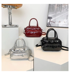 Three glossy Boston mini bags in red, black, and silver shown on geometric display stands