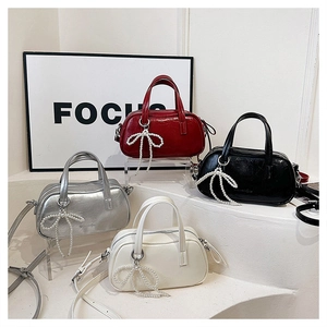 Detail showing quartet of glossy faux leather handbags with pearl bow charms and straps