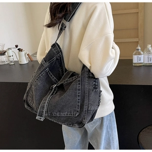 Detail einer großen dunklen Denim-Tasche mit Vintage-Used-Look an der Schulter