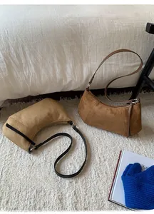 Gros plan des sacs en daim mat en forme de croissant, coloris marron foncé et beige