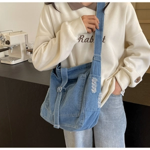 Detail der verstellbaren Metallschnalle und der Distressed-Jeans-Textur einer Umhängetasche