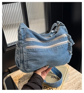 Dettaglio borsa tote in denim blu con doppie cerniere frontali e bordi leggermente sfrangiati