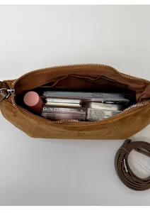 Vue intérieure d'un sac bandoulière en daim marron montrant le rangement des accessoires