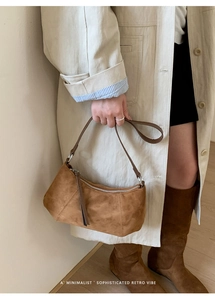 Détail du sac baguette en daim marron avec coutures et fermeture éclair argentée élégante
