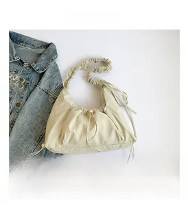 Macro shot of beige nylon pleated shoulder bag with drawstrings and texture detail
