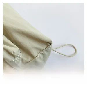 Close-up of beige nylon bag showing fine twill texture and neat white double stitching