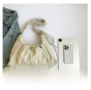 Detail showing beige pleated nylon shoulder bag size compared to tablet and smartphone