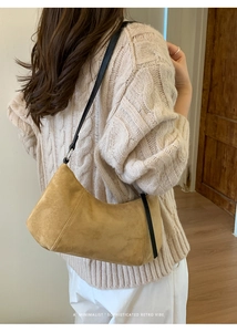 Sac bandoulière rétro en daim moutarde porté sur un pull en maille torsadée beige clair