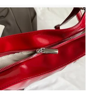 Detail of a red patent leather bag with a smooth silver metal zipper and fabric lining