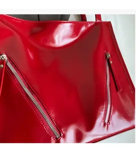 Detail of red patent leather tote bag showing glossy texture and silver zippers