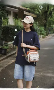 Outdoor crossbody tote bag with orange accents and adjustable strap shown on model