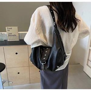 Detail of a black crescent hobo bag with silver star studs on soft leather texture