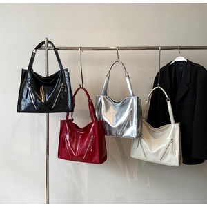 Detailed view of large glossy tote bags with zippers in black, burgundy, silver, and cream