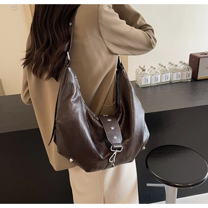 Detail view of large brown hobo bag featuring decorative silver star rivets and soft leather texture