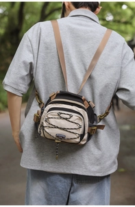 Outdoor crossbody bag in khaki and black with elastic cords shown worn by model