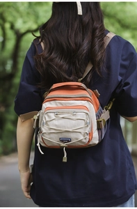 Close-up of hiking crossbody bag with orange contrast, bungee cord, and mesh pocket detail