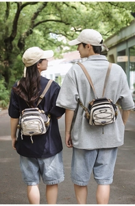Outdoor view of couple wearing matching nylon crossbody bags in beige and grey colorblock