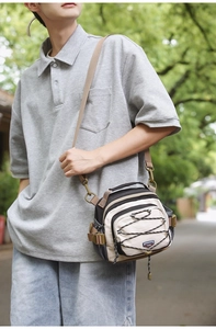 Detail of a functional outdoor crossbody bag showing bungee cords and adjustable strap