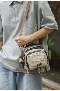 Detail view of a beige functional crossbody bag featuring front elastic drawstring cords