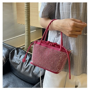 Detail of rose red bucket bag with silver studs, drawstring closure and chain strap