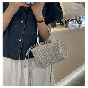 Close-up of sparkling rhinestone bucket bag with drawstring and silver chain strap