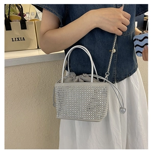 Detail of silver rhinestone bucket bag with metal ring handle and chain strap on model