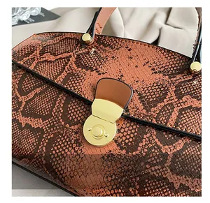 Macro detail of brown snakeskin texture tote bag featuring a gold round twist lock clasp