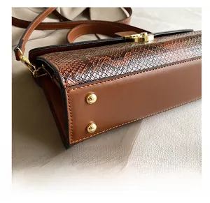 Detail of the brown leather bag showing gold protective studs and snakeskin texture