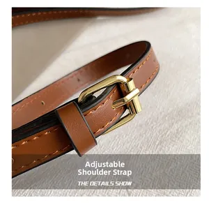 Detail of adjustable brown faux leather strap with gold metal buckle and stitching