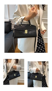 Detail of black faux leather tote with reptile texture and golden circular buckle