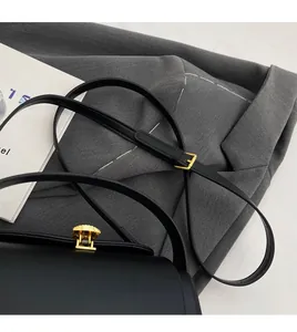 Détail de la bandoulière réglable en cuir noir et de la boucle dorée sur un sac à main
