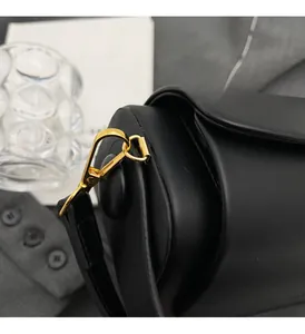 Détail du fermoir en métal doré sur le sac à main cylindrique en cuir noir