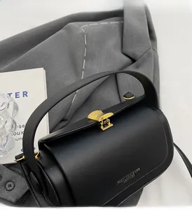 Détail d'un sac à main élégant en cuir noir avec un fermoir en métal doré en forme d'éventail