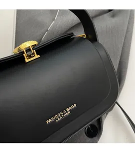 Vue détaillée du sac boîte en cuir noir avec ferrures dorées et texte du logo chic