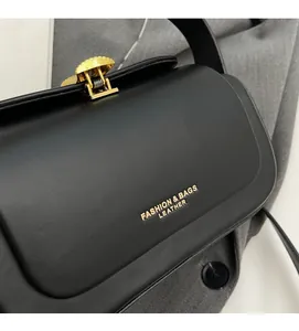 Détail de la texture cuir noir avec boucle dorée et logo imprimé sur le sac à bandoulière