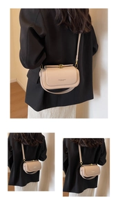 Close-up of beige leather crossbody bag featuring gold hardware lock and logo lettering