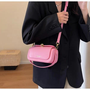 Detail of pink leather flap bag with gold clasp on a model in a black blazer