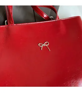 Detail of red glossy shoulder bag with a vintage golden bow and comfortable soft leather texture
