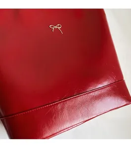 Close-up of red PU leather bag with golden metal bow detail and fine stitching
