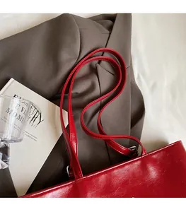 Close-up of red leather tote bag with durable shoulder strap and metallic buckle detail